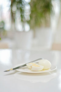 Boiled eggs on a kitchen table, healthy protein rich breakfast. plate, a knife, white background.