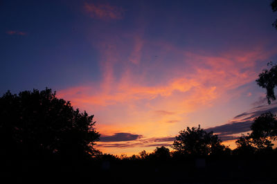 Low angle view of silhouette trees against dramatic sky