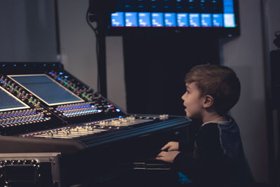 Side view of boy using sound mixer in studio