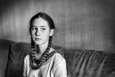 Portrait of young woman standing against wall