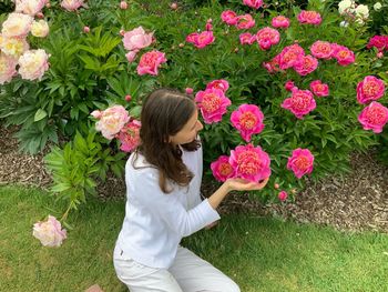 Woman standing by pink flowering plants