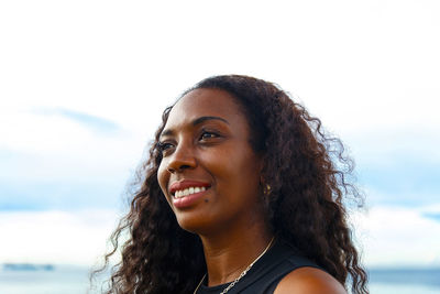 Portrait of smiling young woman against sky