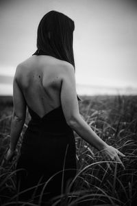 Rear view of woman standing on field against sky