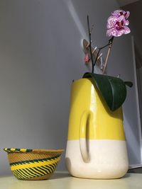 Close-up of yellow flower on table against wall