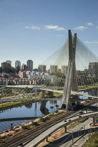 Bridge over city by buildings against sky