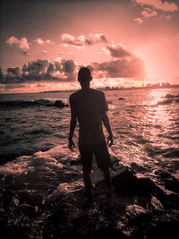 Rear view of man standing on beach during sunset