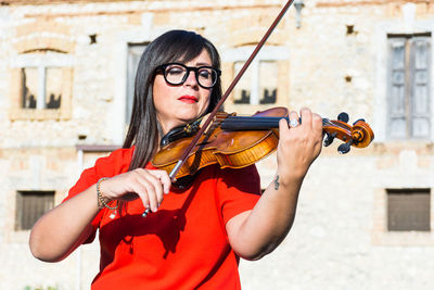 Woman playing violin against building