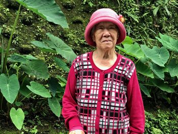 Senior woman wearing hat while standing by plants