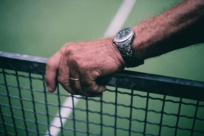 Cropped image of hand holding fence