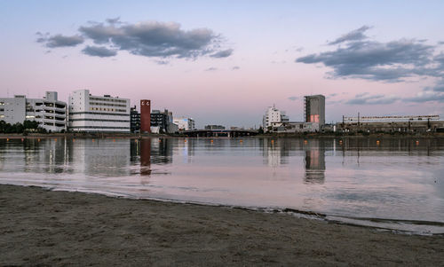 Scenic view of river by buildings against sky