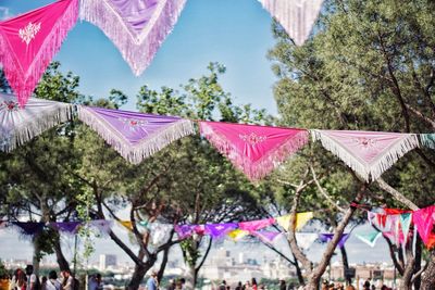 Low angle view of multi colored flags hanging against trees