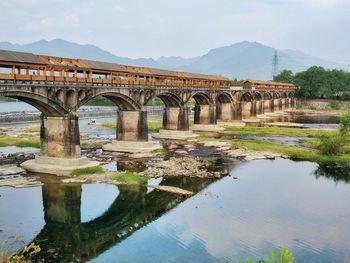 Arch bridge over river against sky