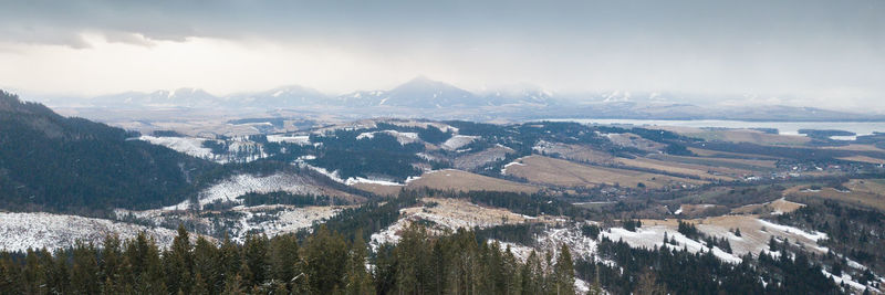 Aerial view on snowy valley with mountain range shrouded in clouds in background, slovakia, europe