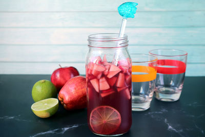 Bottle of homemade red wine sangria with two glasses and fruits on the table