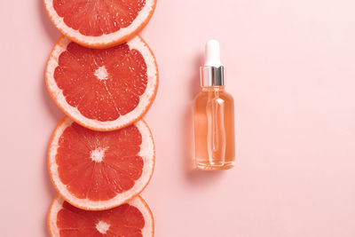 Bottle with dropper of aroma essential oil wich grapefruit fresh slice. flat lay, top view 