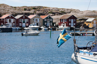 Boats moored on sea by mountain against sky