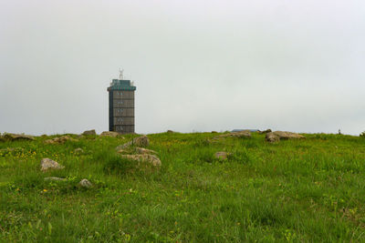 Lighthouse on field against sky