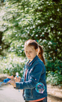 Portrait of young woman standing against plants