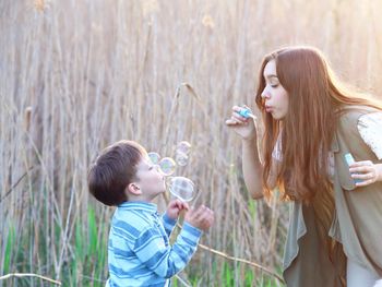 Sister and brother blowing bubbles against plants