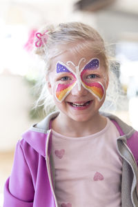 Portrait of smiling girl with painted butterfly on face