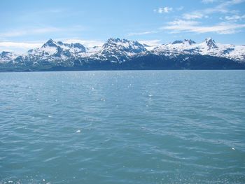 Scenic view of sea and snowcapped mountains against sky