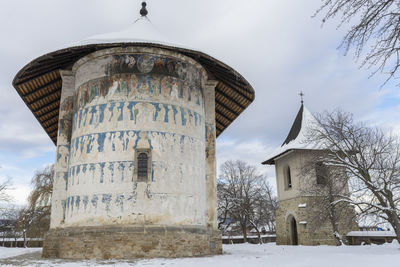 Church by building against sky during winter