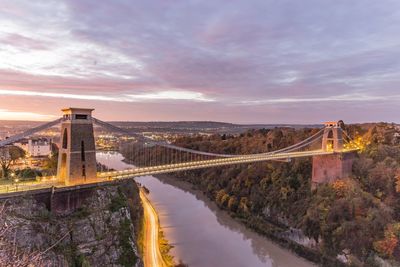 Bridge over river against sky during sunset