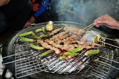 Midsection of person preparing food on barbecue grill