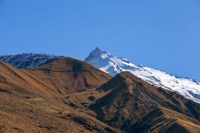 Scenic view of snowcapped mountains against clear blue sky