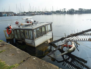 Abandoned fishing boat sinking by pier in lake