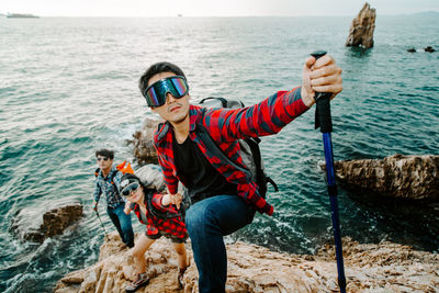 Rear view of men holding rock in sea