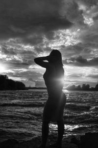 Silhouette man standing at beach against sky during sunset