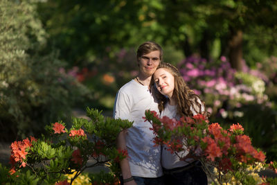 Portrait of couple standing amidst flowers at park