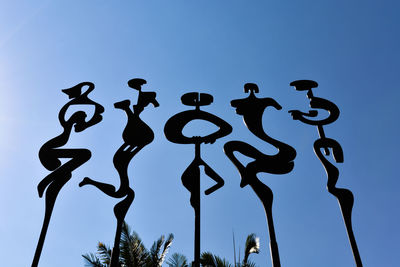 Low angle view of silhouette sculpture against clear blue sky