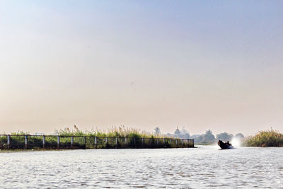 Man by river against clear sky