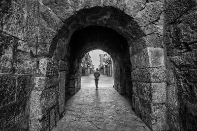 Rear view of man walking in tunnel