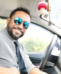 Portrait of man wearing sunglasses sitting in car