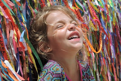 Close-up of happy girl against multi colored ribbons