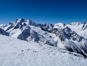 Scenic view of snowcapped mountains against clear blue sky