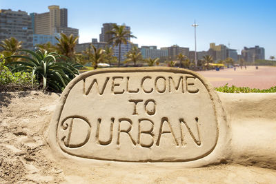 Close-up of information sign on beach against buildings in city