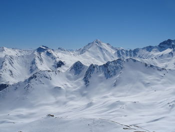 Scenic view of snowcapped mountains against clear blue sky