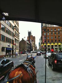 Cars on city street against sky