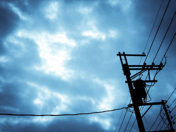 Low angle view of electricity pylon against cloudy sky