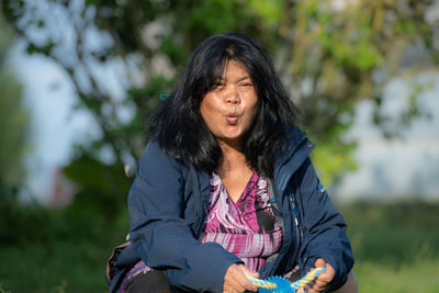 An asian middle aged woman calling a puppy.