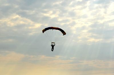 Person paragliding against cloudy sky