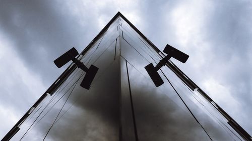 Low angle view of crane by building against sky