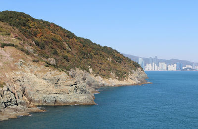 Scenic view of sea and cityscape against clear sky