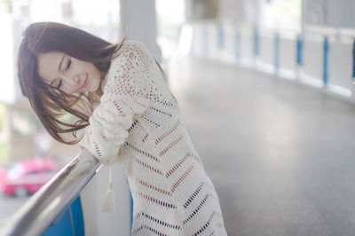 Beautiful young woman leaning on railing of footbridge