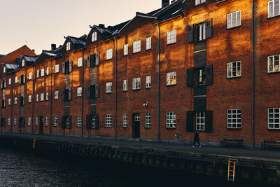 Buildings by canal against sky in city