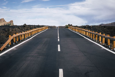 Diminishing perspective of empty road against cloudy sky